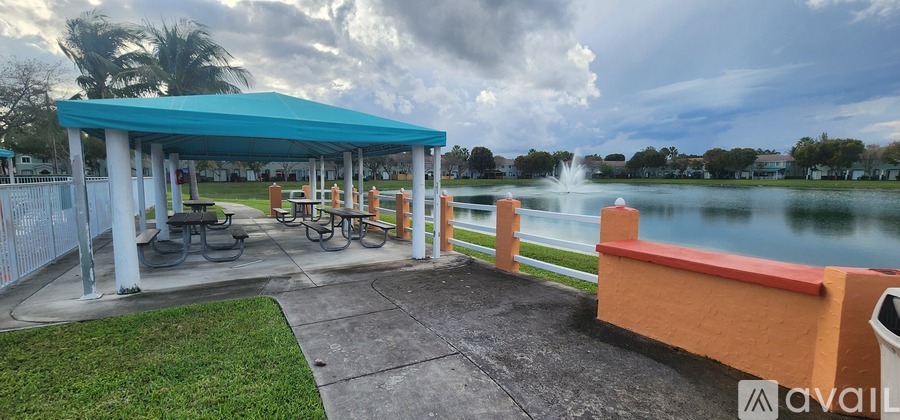 A gazebo with picnic tables is situated by a lake.