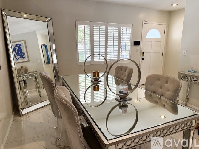 A modern dining room with a glass table and chairs.