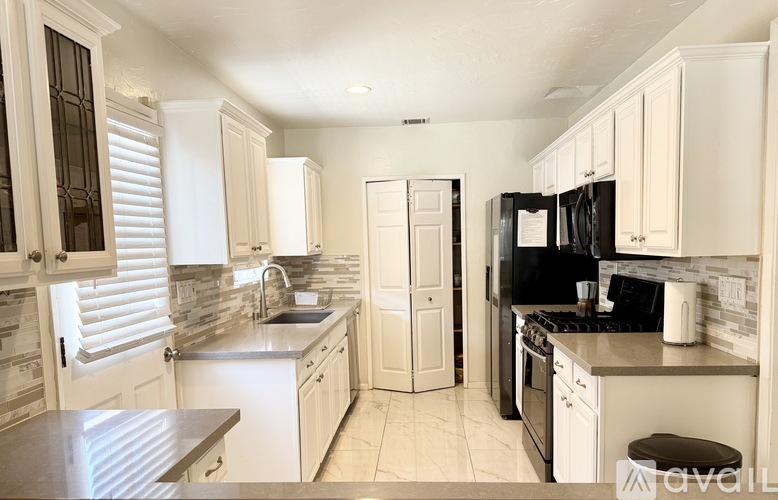 A kitchen with white cabinets and black appliances.