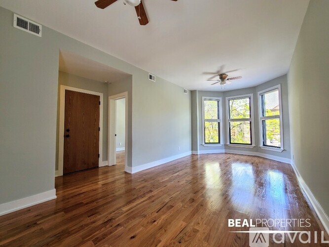 A spacious room with wooden floors and a ceiling fan.