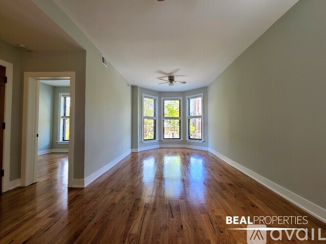 A spacious room with wooden floors and a ceiling fan.
