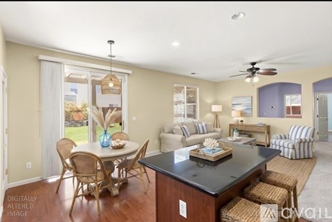 A dining room with a table set for six and a kitchen area with a counter.