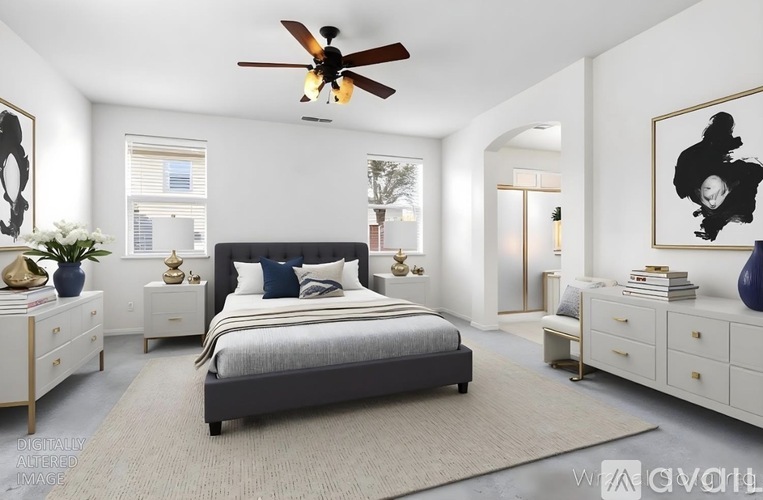 A bedroom with a large bed, a ceiling fan, and a painting on the wall.