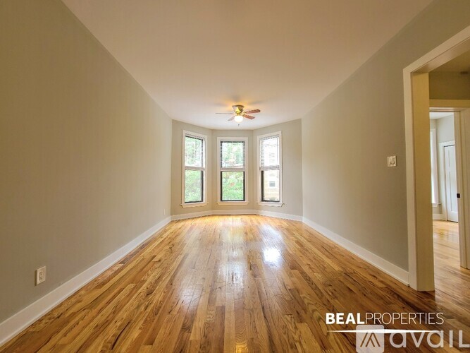A spacious room with wooden floors and a ceiling fan.