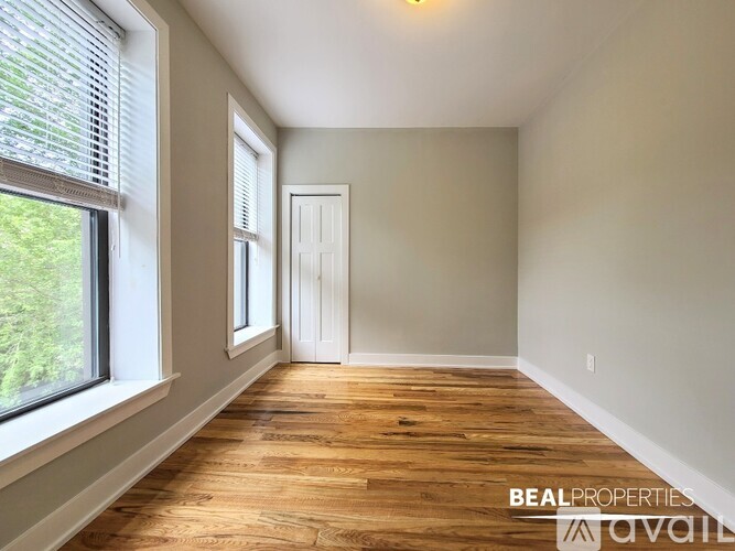 A room with wooden flooring and a white door is available for rent.