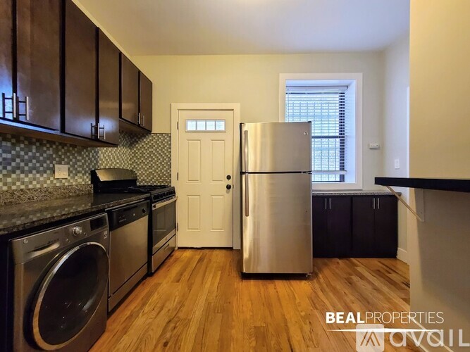 A kitchen with a stainless steel refrigerator and a washing machine.