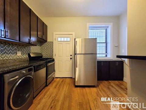 A kitchen with a stainless steel refrigerator and a washing machine.