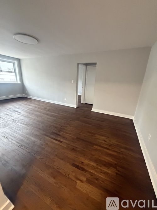 A room with wooden flooring and a doorway leading to another room.