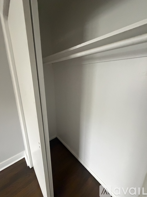 A white closet with a wooden floor.