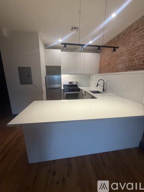 A kitchen with a white countertop and a brick wall.