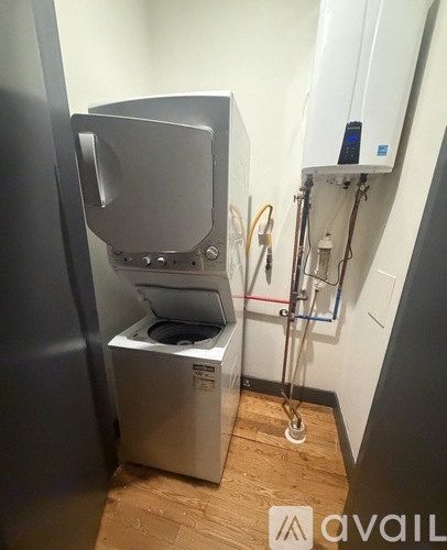 A white industrial sized washing machine in a narrow room.