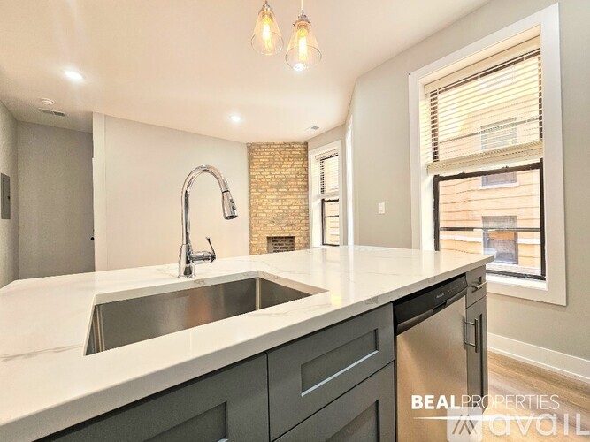 A modern kitchen with a brick accent wall and a large window.