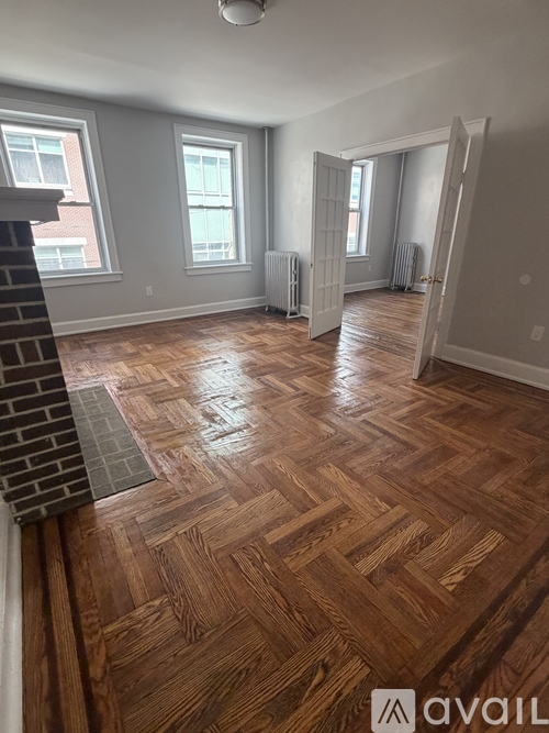 A room with wooden flooring and a brick fireplace.