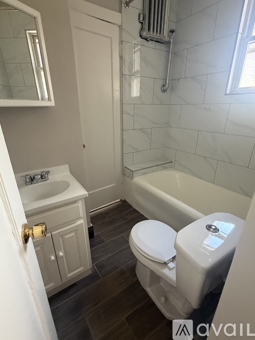 A white toilet with a white bath tub in a bathroom.