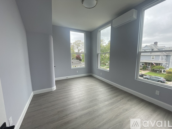 A spacious room with grey walls and a wooden floor.