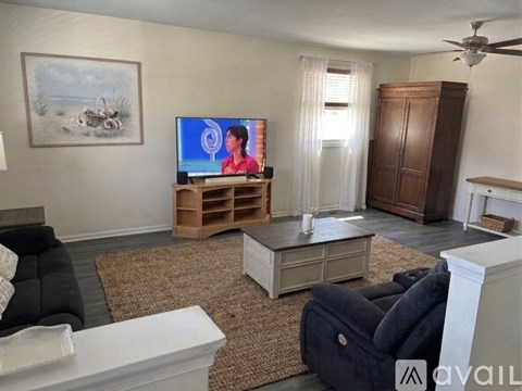 A woman is sitting on a couch watching television in a living room.