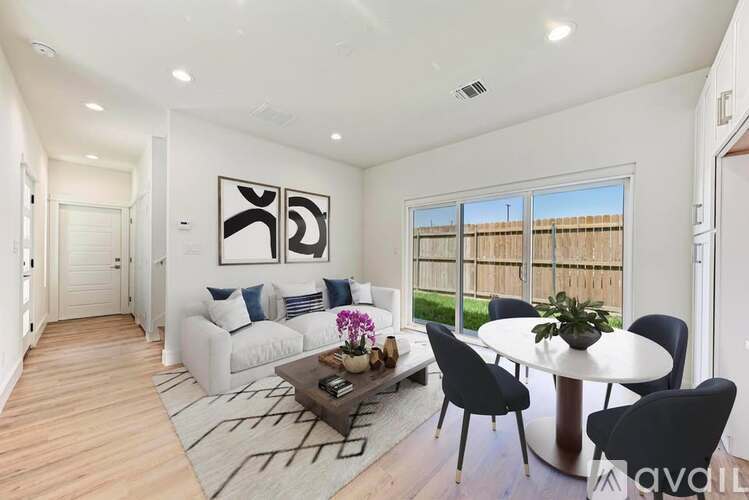 A modern living room with a white sofa, a coffee table, and a dining table set up.