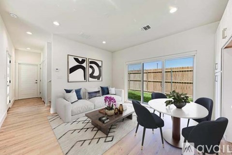 A modern living room with a white sofa, a coffee table, and a dining table set up.