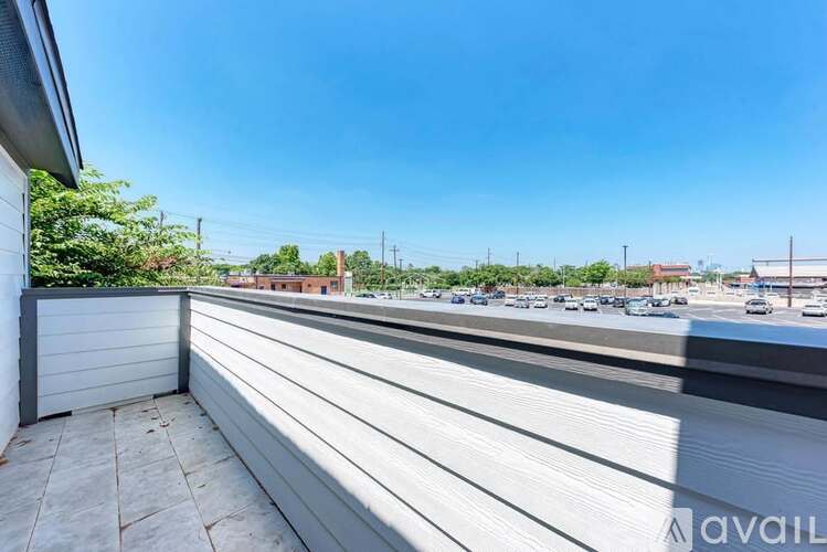 A balcony with a view of a parking lot and buildings.
