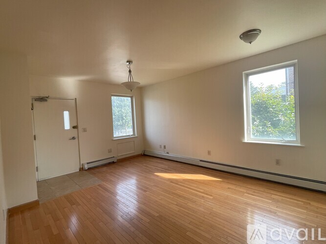 A room with wooden floors and a window with a view of trees.
