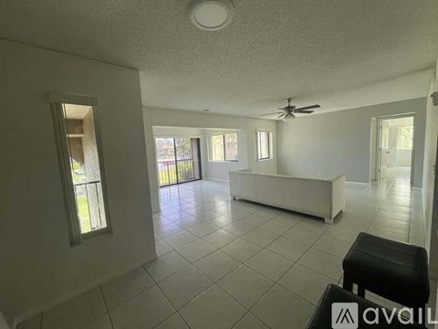 A spacious living room with a white sofa and a ceiling fan.