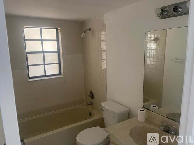 A bathroom with a toilet, a bathtub, and a window.