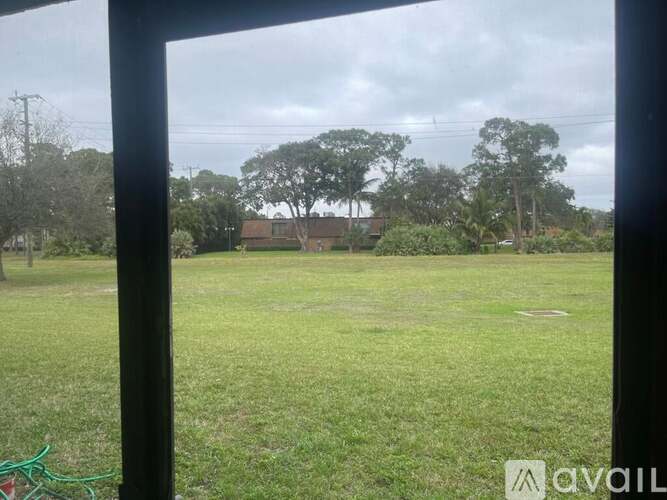 A grassy field with trees and a house in the distance.