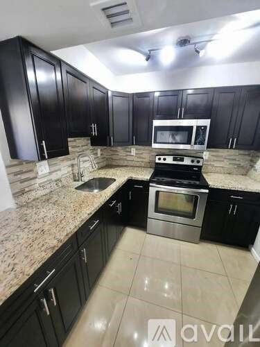 A kitchen with black cabinets and granite countertops.