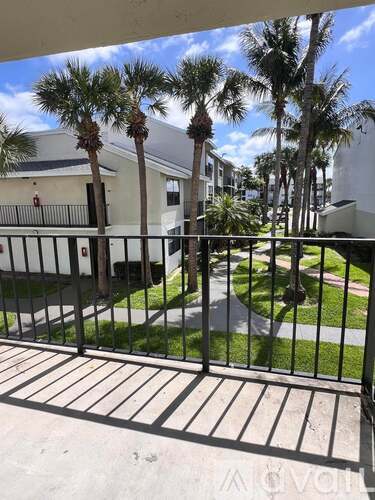 A view from a balcony looking out at a building and palm trees.