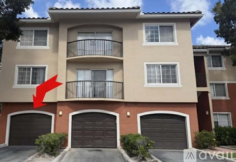 A beige and brown apartment building with a red arrow pointing to the second floor balcony.