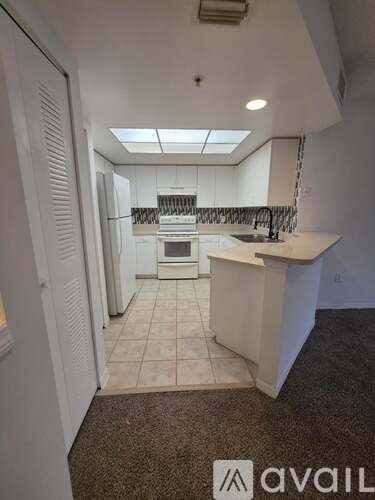 A kitchen with white cabinets and a white island with a sink.