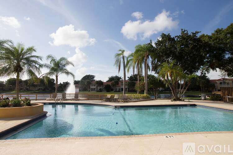 A pool surrounded by palm trees and a fountain.