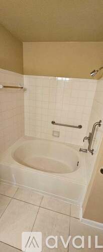 A white bathtub with a shower head and a towel bar.