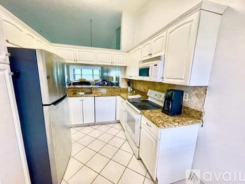 A kitchen with white cabinets and a black refrigerator.
