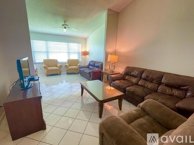 A living room with a brown couch, a coffee table, and a television.