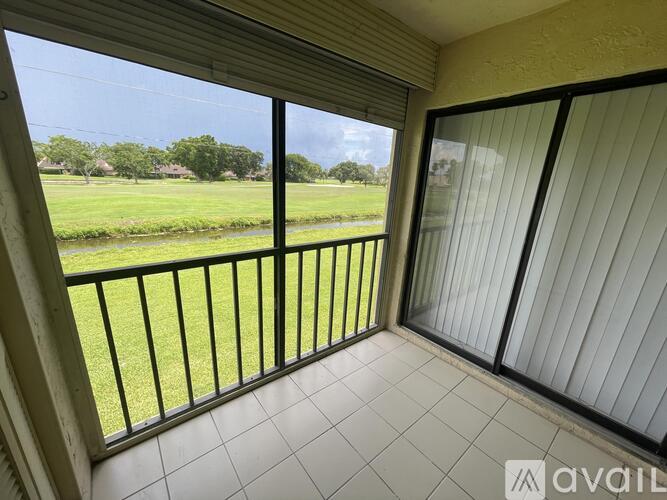 A balcony with a view of a green field and trees.