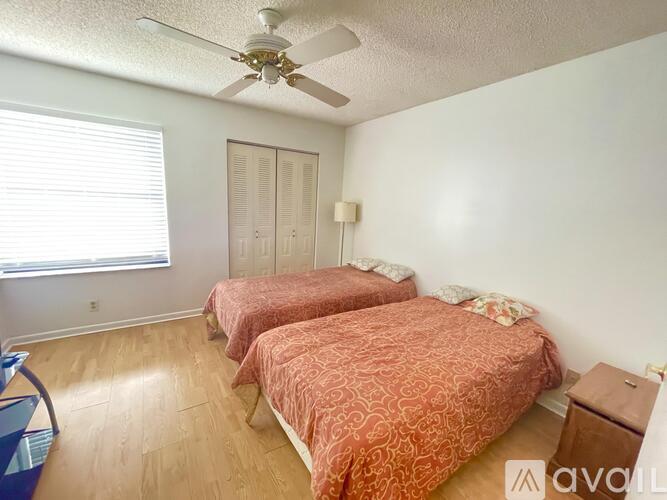 A bedroom with two beds and a ceiling fan.