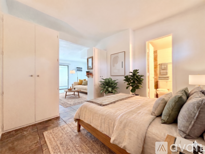 A bedroom with a large bed and a plant on the windowsill.