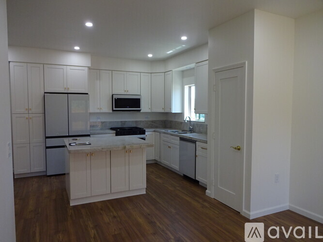 A kitchen with white cabinets and a wooden floor.