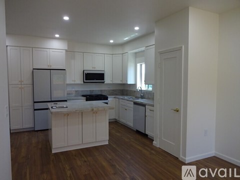 A kitchen with white cabinets and a wooden floor.