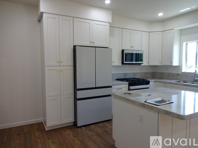 A kitchen with white cabinets and a refrigerator.