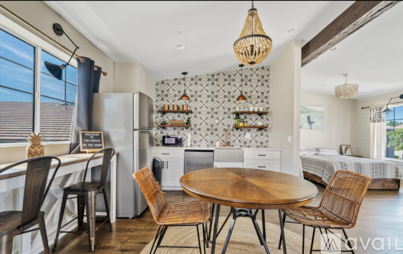 A kitchen with a table and chairs in the foreground and a bedroom in the background.