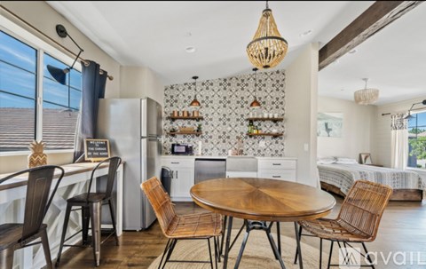 A kitchen with a table and chairs in the foreground and a bedroom in the background.