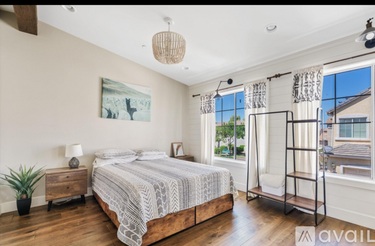 A bedroom with a large bed, a wooden dresser, and a window with curtains.