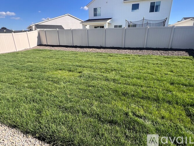 A white house with a white fence and green grass in front.