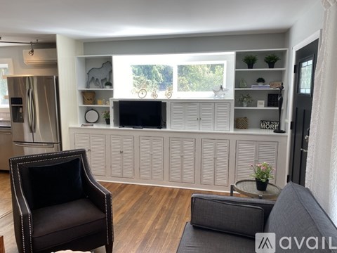 A black chair sits in a living room with a black couch and a coffee table.