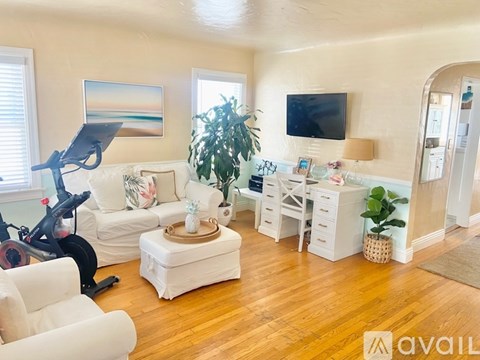 A living room with a white couch, a white coffee table, a white desk, and a white chair.