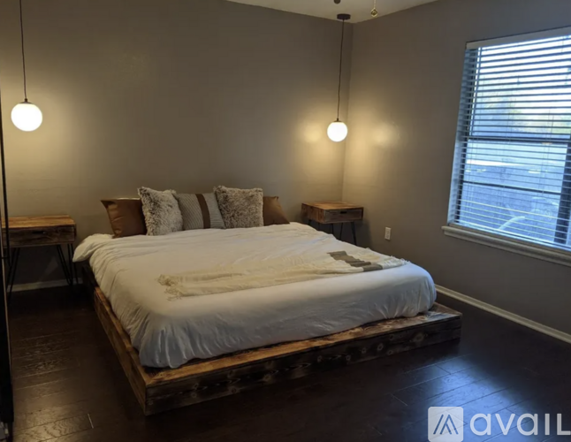 A bedroom with a bed, nightstands, and a window.