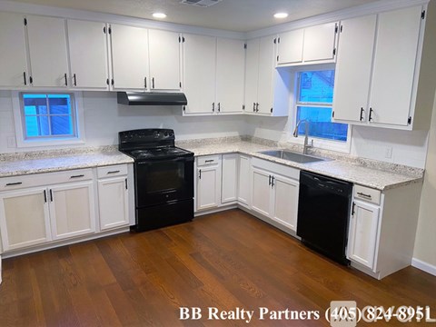 A kitchen with white cabinets and black appliances.