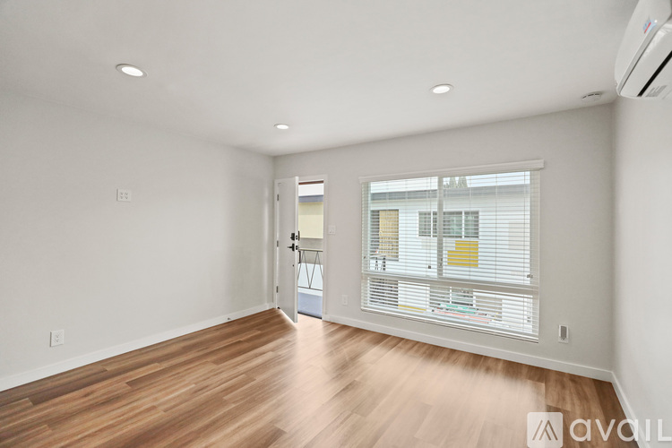 A spacious room with wooden floors and a window with blinds.
